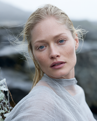 Portrait de femme blonde aux yeux bleus, fond rocheux nordique